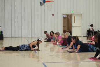 Yoga instructor Lisa Lizotte leads school district employees through stretches Tuesday afternoon in the Parkview Baptist Church gymnasium. Twenty-five people attended the first yoga class, offered as part of a school district wellness initiative. (TONY BRITT/Lake City Reporter)