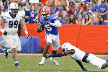 Florida quarterback Emory Jones (5) scrambles for yardage as he gets past Samford defensive tackle Seth Simmer (99) and cornerback Coutrell Plair, right, during Saturday's game in Gainesville. (JOHN RAOUX/Associated Press)