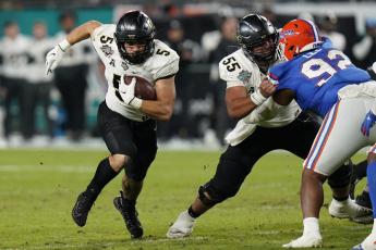 Central Florida running back Isaiah Bowser (5) follows a block by offensive lineman Matthew Lee (55) on Florida defensive lineman Jalen Lee during the Gasparilla Bowl on Thursday in Tampa. (CHRIS O’MEARA/Associated Press)