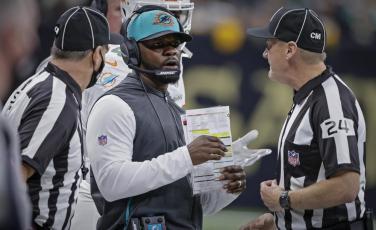 Miami Dolphins head coach Brian Flores, center, talks to down judge David Oliver (24) during a game against the New Orleans Saints on Dec. 27 in New Orleans. (AP FILE)