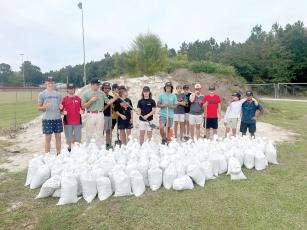 Members of the Fort White baseball team show off a number of the sandbags they helped fill at the South Columbia Sports Complex on Tuesday afternoon. The Indians helped fill and load sandbags for area residents in prep for Hurricane Ian. (COURTESY)
