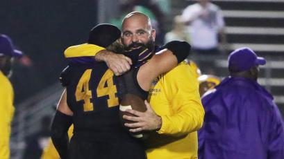 Columbia defensive coordinator John Woodley hugs defensive tackle Caden Bolstein (44) after Columbia stopped Choctaw on fourth down in overtime of Friday’s Region 1-3S final. (BRENT KUYKENDALL/Lake City Reporter)