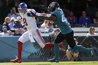 New York Giants quarterback Daniel Jones scrambles away from Jacksonville Jaguars linebacker Josh Allen on Sunday in Jacksonville. (PHELAN M. EBENHACK/Associated Press)
