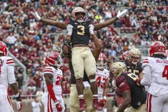 Florida State running back Trey Benson (3) is lifted by offensive lineman Jazston Turnetine in celebration after scoring a touchdown during Saturday's game in Tallahassee. (GARY MCCULLOUGH/Associated Press)
