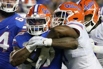 Florida running back Cam Carroll (left) is tackled by Florida edge Kelby Collins during the team's annual Orange and Blue spring game on April 13 in Gainesville. (JOHN RAOUX/Associated Press)