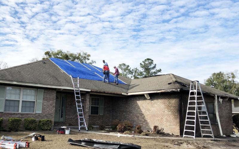 Among those volunteering to patch the roof of a home hit by a plane Saturday were Bill Brinkley (from left), Alvin Hitson and Mark Nodes. Photo by Robert Bridges/Lake City Reporter