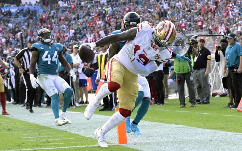 San Francisco 49ers wide receiver Deebo Samuel scores a 25-yard touchdown in front of Jacksonville Jaguars safety Rayshawn Jenkins, center, and linebacker Myles Jack (44) during Sunday’s game in Jacksonville. (PHELAN M. EBENHACK/Associated Press)