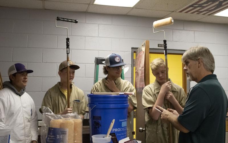 Columbia High building and construction teacher Scott Dockery (right) gives directions to Tyler Moore (from left), Chase Bedenbaugh, Cameron Saunder and Shawn Cuchens as they prepare to begin the painting portion of the shop renovation with painting supplies graciously donated by Sherwin Williams. (COURTESY)