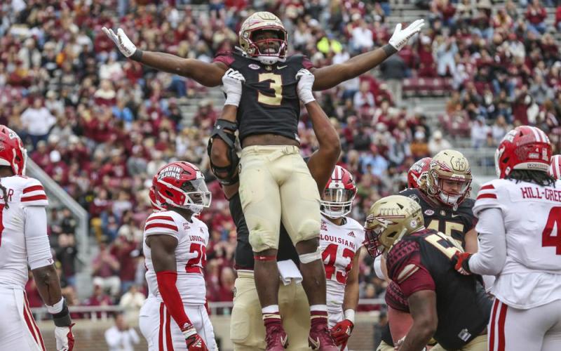 Florida State running back Trey Benson (3) is lifted by offensive lineman Jazston Turnetine in celebration after scoring a touchdown during Saturday's game in Tallahassee. (GARY MCCULLOUGH/Associated Press)