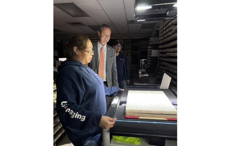 Columbia County Clerk of Court Jay Swisher (center) watches as U.S. Imaging’s Felicia Valdez scans one of the county’s bound historical records in the records vault at the Columbia County Courthouse Thursday. U.S. Imaging’s Brandon Valdez looks on. (JAMIE WACHTER/Lake City Reporter)