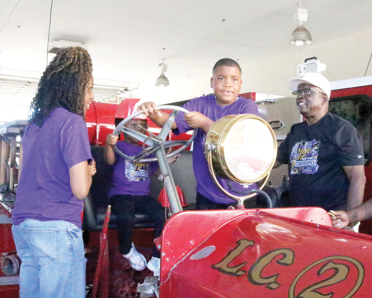 De’ Mari Jackson (third from left), grabs the steering wheel on the antique fire truck as the Lake City Department during a  visit Thursday. Jackson, who has Kleefstra Syndrome, visited the LCFD on Kleestra Syndrome Awareness Day. (TONY BRITT/Lake City Reporter)