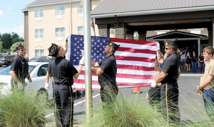 American Legion Post 57 Honor Guard members and members of the Liberty Division Sea Cadets, raise a new flag at the Best Western Plus hotel in Lake City on Friday morning in front of a group of onlookers such as other Post 57 members, hotel staff and hotel guests. (TONY BRITT/Lake City Reporter)