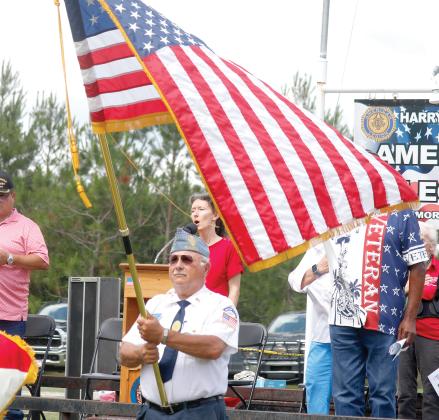 Joy Geiger sings the national anthem during Monday’s Memorial Day ceremony at the American Legion Harry C. Gray II Memorial Post 107 in McAlpin as the American flag waves in front of her. (JAMIE WACHTER/Lake City Reporter)