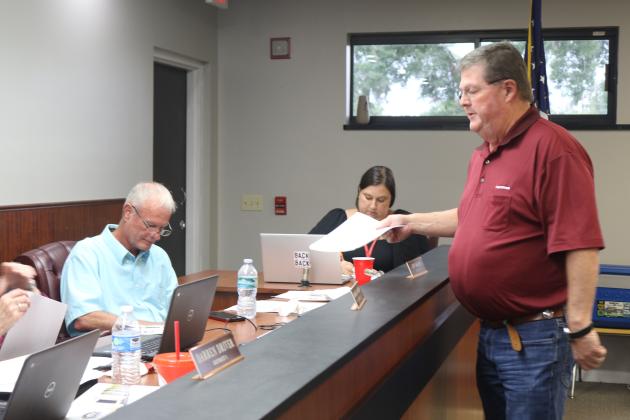 Eddie Dixon with Culpepper Construction provides documents to the Lafayette County School Board as he updated them on the status of state funding for a new PK-12 school for the district at Tuesday’s board meeting. (TONY BRITT/Lake City Reporter)