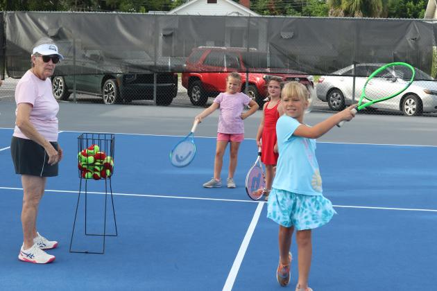 Marcia Kazmierski (left) watches as Jensen Haire, 8, hits a tennis ball during the 10th annual James Montgomery Tennis Camp at Youngs Park on Thursday. (TONY BRITT/Lake City Reporter)