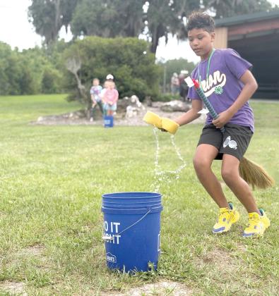 Zayden Jones learns the art of broom handling while participating in a relay race during Columbia County 4-H’s School of Life Skills for Magical Beings camp earlier this month. (COURTESY)