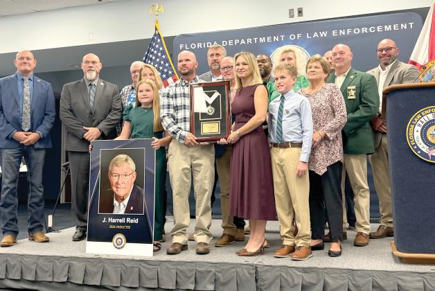 Kathryn Land and J. Reid, former Hamilton County Sheriff Harrell’s Reid’s children, hold his encased medallion after he was posthumously inducted into the Florida Law Enforcement Officers Hall of Fame on Saturday. Land and Reid were surrounded by family members and past and present members of the Hamilton County Sheriff’s Office. (COURTESY)