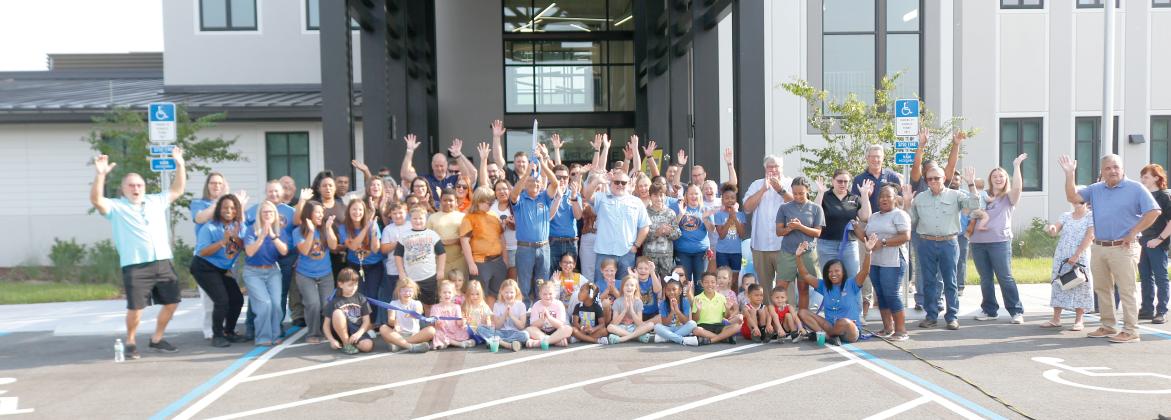 Columbia County School Board member Keith Hudson holds up the scissors after cutting the ribbon to open up the new Eastside Elementary School on Tuesday morning. Hudson is joined by students, faculty and staff at Eastside as well as school district officials and members of the Gilbane Construction company that built the new school. (JAMIE WACHTER/Lake City Reporter)