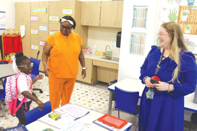 Jordynn Cray (left) prepares to get settled into the kindergarten classroom of Brittany Townsend (right) during the first day of classes at the new Eastside Elementary School. (TONY BRITT/Lake City Reporter)