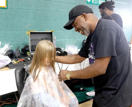 Lilly Miles, 6, gets a face frame and trim from local barber Tyrone Mullins during the Community Barbers Back-to-School Bash at the Richardson Community Center on Sunday. More than 1,000 people attended the event. (TONY BRITT/Lake City Reporter)