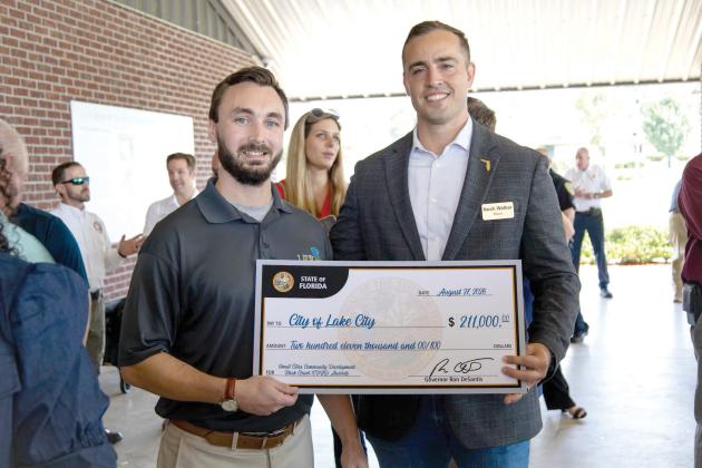 Lake City Mayor Noah Walker (right) and Dakota Braun, the city’s grant writer, hold the city’s ceremonial check for $211,000 that it received Thursday for a street paving project. (COURTESY CITY OF LAKE CITY)