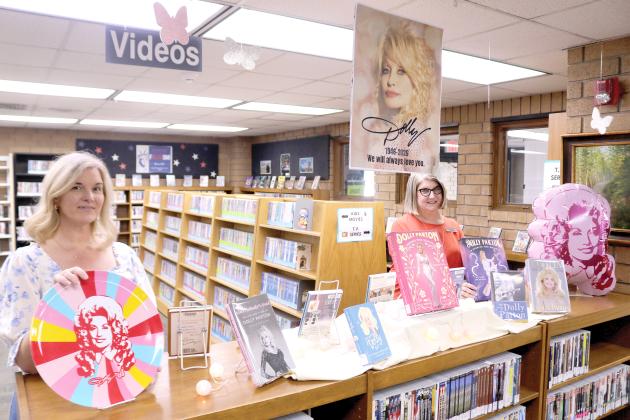 Columbia County Public library employees Heather Blair and Katrina Evans show off one of the Dolly Parton displays that were recently added to the main branch library on Tuesday. (TONY BRITT/Lake City Reporter)