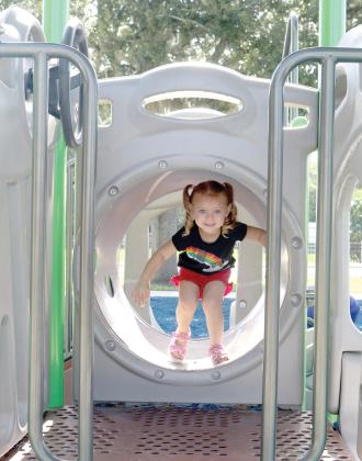 Ellie Davis makes her way through a tunnel on a piece of equipment at Sallie Mae Jerry Park on Friday. (TONY BRITT/Lake City Reporter)