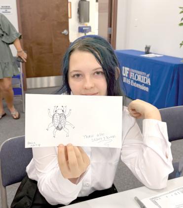 A Columbia County 4-H Arachnerds member shows off her original beetle-inspired creation. Designing imaginary bugs gave club members a chance to combine creativity with what they were learning about entomology and arthropod characteristics. (COURTESY)