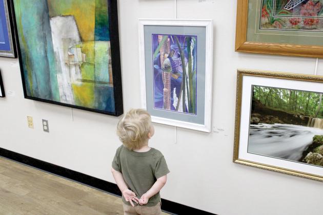 A young art fan checks out some of the works in last year’s Autumn Artfest, the fine arts exhibition sponsored by the Live Oak Artists Guild. The 28th annual Artfest opens Saturday at the Live Oak branch of the Suwannee River Regional Library. (COURTESY)