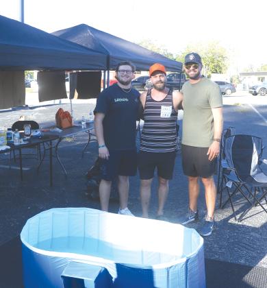 Tucker Williams (from left), Zach Zedar and Shayne Barber gather under the shade of their tent on the corner of SW Baya Avenue and SW Main Boulevard. The trio offered free hot dogs, Bibles and prayers for passers by on Thursday. (MORGAN MCMULLEN/Lake City Reporter)