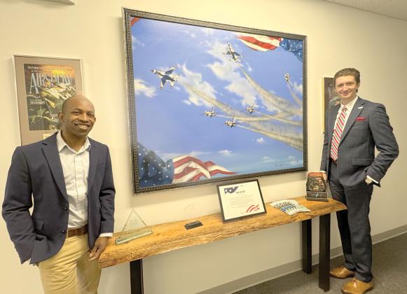 Pedro Jermaine, an internationally known artist and Lake City resident (left), is pictured with Columbia County Tourist Development Council Executive Director Cody Gray after loaning the Visit Lake City Welcome Center and TDC office his ‘BOOM’ painting that was created in honor of the 2016 Gateway to Florida Airshow. (JAMIE WACHTER/Lake City Reporter)