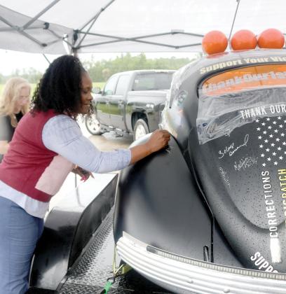 Lake City Vice Mayor Chevella Young signs the Thank Our First Responders car during its stop Thursday at the Columbia County Sheriff’s Office. (TONY BRITT/Lake City Reporter)