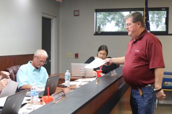 Eddie Dixon with Culpepper Construction provides documents to the Lafayette County School Board as he updated them on the status of state funding for a new PK-12 school for the district at Tuesday’s board meeting. (TONY BRITT/Lake City Reporter)