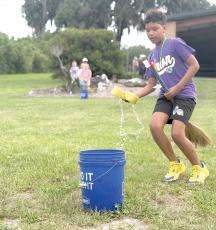 Zayden Jones learns the art of broom handling while participating in a relay race during Columbia County 4-H’s School of Life Skills for Magical Beings camp earlier this month. (COURTESY)