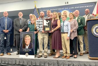 Kathryn Land and J. Reid, former Hamilton County Sheriff Harrell’s Reid’s children, hold his encased medallion after he was posthumously inducted into the Florida Law Enforcement Officers Hall of Fame on Saturday. Land and Reid were surrounded by family members and past and present members of the Hamilton County Sheriff’s Office. (COURTESY)