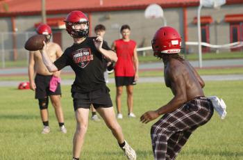 Lafayette quarterback Tucker Higginbotham throws a pass while being rushed by defensive end Zamarion Hawkins during Tuesday’s practice. (JAMIE WACHTER/Lake City Reporter)