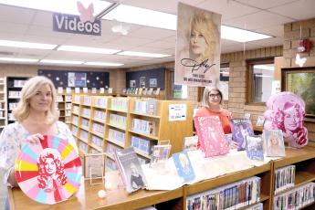 Columbia County Public library employees Heather Blair and Katrina Evans show off one of the Dolly Parton displays that were recently added to the main branch library on Tuesday. (TONY BRITT/Lake City Reporter)