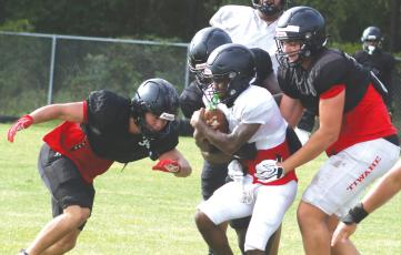 Fort White linebacker Kayden Ireland (left) and defensive lineman Cillian Sheehan (right) wrap up running back Jeremiah Taylor during Monday’s practice. (MORGAN MCMULLEN/Lake City Reporter)