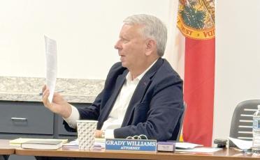 North Florida Water Utilities Authority Attorney Grady Williams holds up a copy of the 2025 interlocal agreement between the authority and both Columbia and Suwannee counties about operation and transfer of the utility assets in both counties. (JAMIE WACHTER/Lake City Reporter)