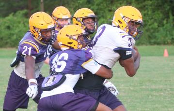 Columbia receiver Zion Walker fights to break away from a tackle from defensive back Mekah Combs-Turner (16) as defensive backs Jermone Carter (21) and Chris Austin (back) give chase during Wednesday’s practice. (JORDAN KROEGER/Lake City Reporter)