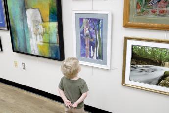 A young art fan checks out some of the works in last year’s Autumn Artfest, the fine arts exhibition sponsored by the Live Oak Artists Guild. The 28th annual Artfest opens Saturday at the Live Oak branch of the Suwannee River Regional Library. (COURTESY)