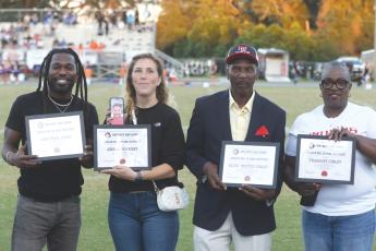 Fort White Hall of Fame inductees Jonathan James (left), Jordan Dewhirst (on phone), Elvis ‘Buster’ Conley and Tramaine Conley were honored with plaques ahead of Friday’s football game against Taylor County. Tramaine Conley, who passed in 2022 at age 38, is represented by his mother, Phyllis Conley. Former baseball player Tyler Shelnut, who was also inducted into the Hall of Fame, could not attend. (MORGAN MCMULLEN/Lake City Reporter)