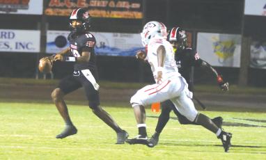 Fort White quarterback Chance Johnson rolls out to avoid pressure from Santa Fe last Friday. (MORGAN MCMULLEN/Lake City Reporter)