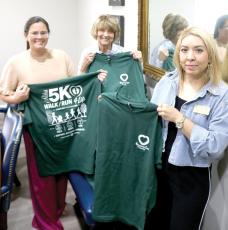 Lake City Pregnancy Care Center staff members Brittany Schied (from left), Charlene Brown and Rosalindo Caballero display T-shirts for the upcoming Pregnancy Care Center 5K Walk/Run 4 Life. (TONY BRITT/Lake City Reporter)