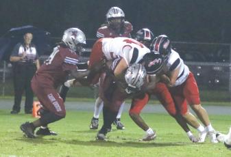 Fort White linebacker Kayden Ireland hangs on the back of Madison County quarterback Chad Mitchell as other Indians converge last Thursday. (MORGAN MCMULLEN/Lake City Reporter)