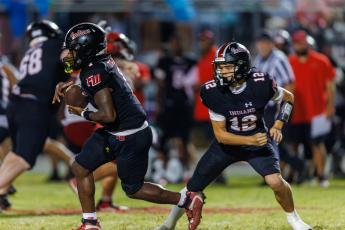 Fort White quarterback Carter Wheeler (12) hands the ball off to running back John’l Lawson during last week’s 29-22 win over Lafayette. (JACK HOWDESHELL/Lake City Reporter)