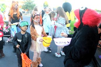 Parker Smith (from left), 5, and Jade Smith, 7, collect candy from Luz Perez of Marie’s Mexican Treats while at the Texas Roadhouse Trunk or Treat event on Tuesday evening. (TONY BRITT/Lake City Reporter)