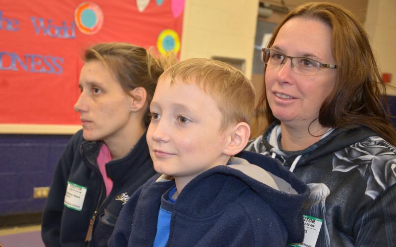 Hunter Dover, soon to turn 9, sits in his grandmother’s lap during a presentation at Five Points Elementary welcoming him back to school after a long absence. (CARL MCKINNEY/Lake City Reporter)