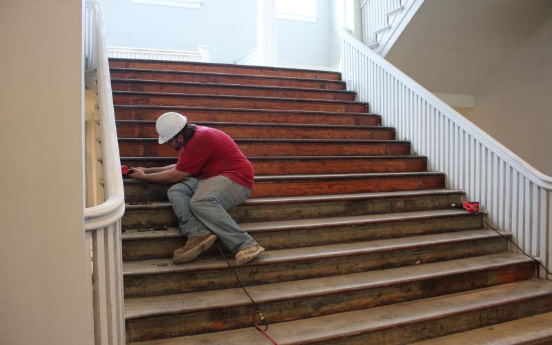 A construction worker uses a heat gun to remove carpet glue on a staircase at the Blanche Hotel so the stairs can be sanded then refinished. (TONY BRITT/Lake City Reporter)