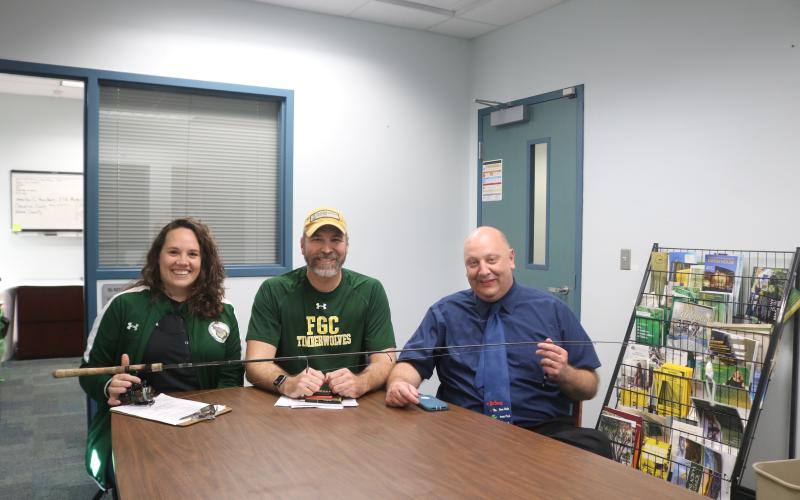 Rebecca Golden (from left), FGC athletic coordinator, sits with Rob Chapman, FGC coordinator of enrollment and marketing and webmaster, and Lawrence Barrett, FGC president, as the three hold a fishing rod and reel during the school’s announcement on Friday that it will launch a competitive bass fishing team. The FGC Bassmasters plan to compete during the 2020-21 school year. (TONY BRITT/Lake City Reporter)